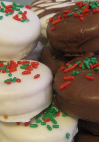A pile of Ritz dipped in white and dark chocolate with green and red sprinkles on top