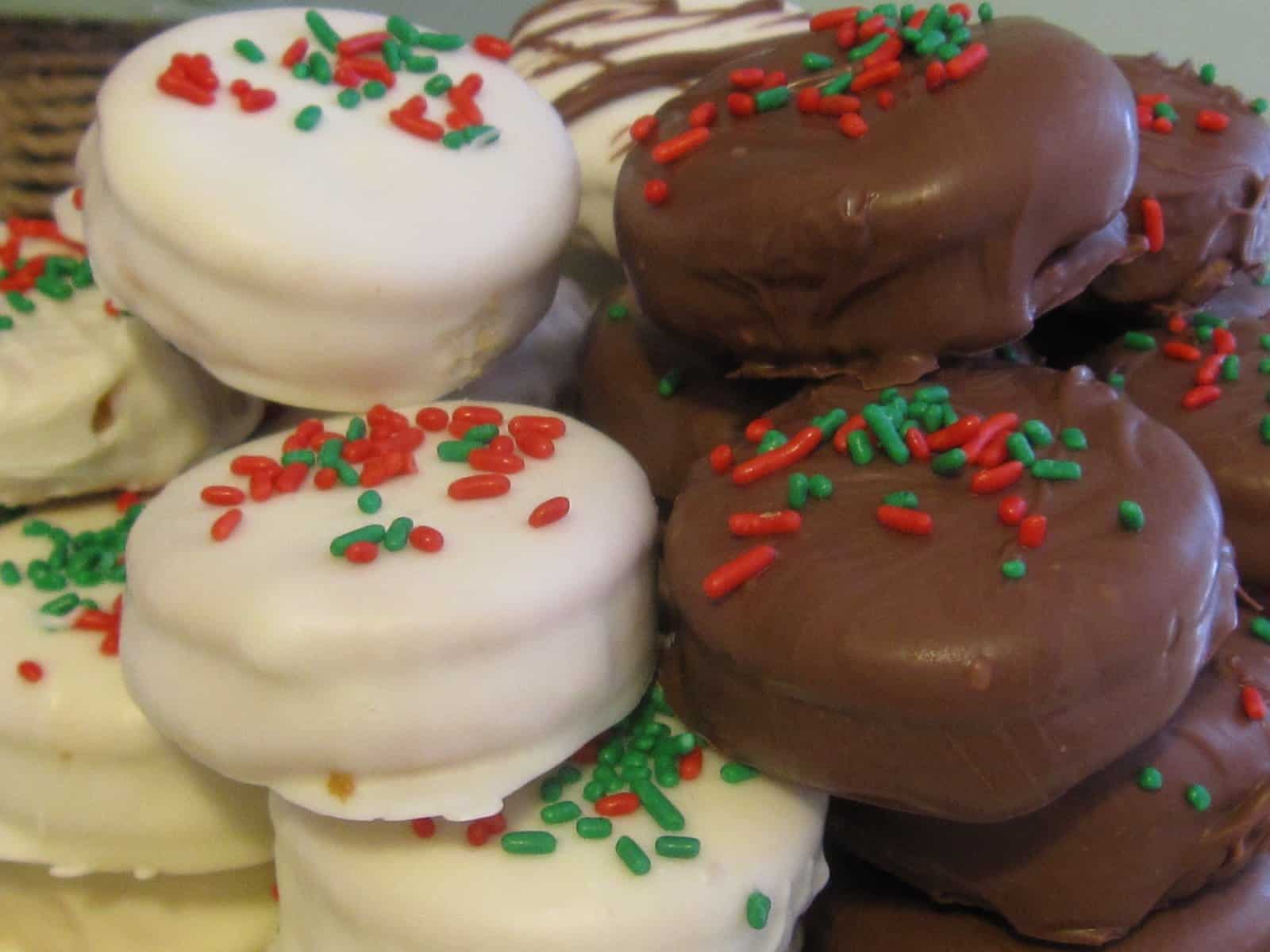 A pile of Ritz dipped in white and dark chocolate with green and red sprinkles on top