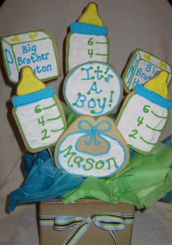 Seven Baby-Themed Sugar Cookies Sticking Out of a Square Bowl with a Bow on It