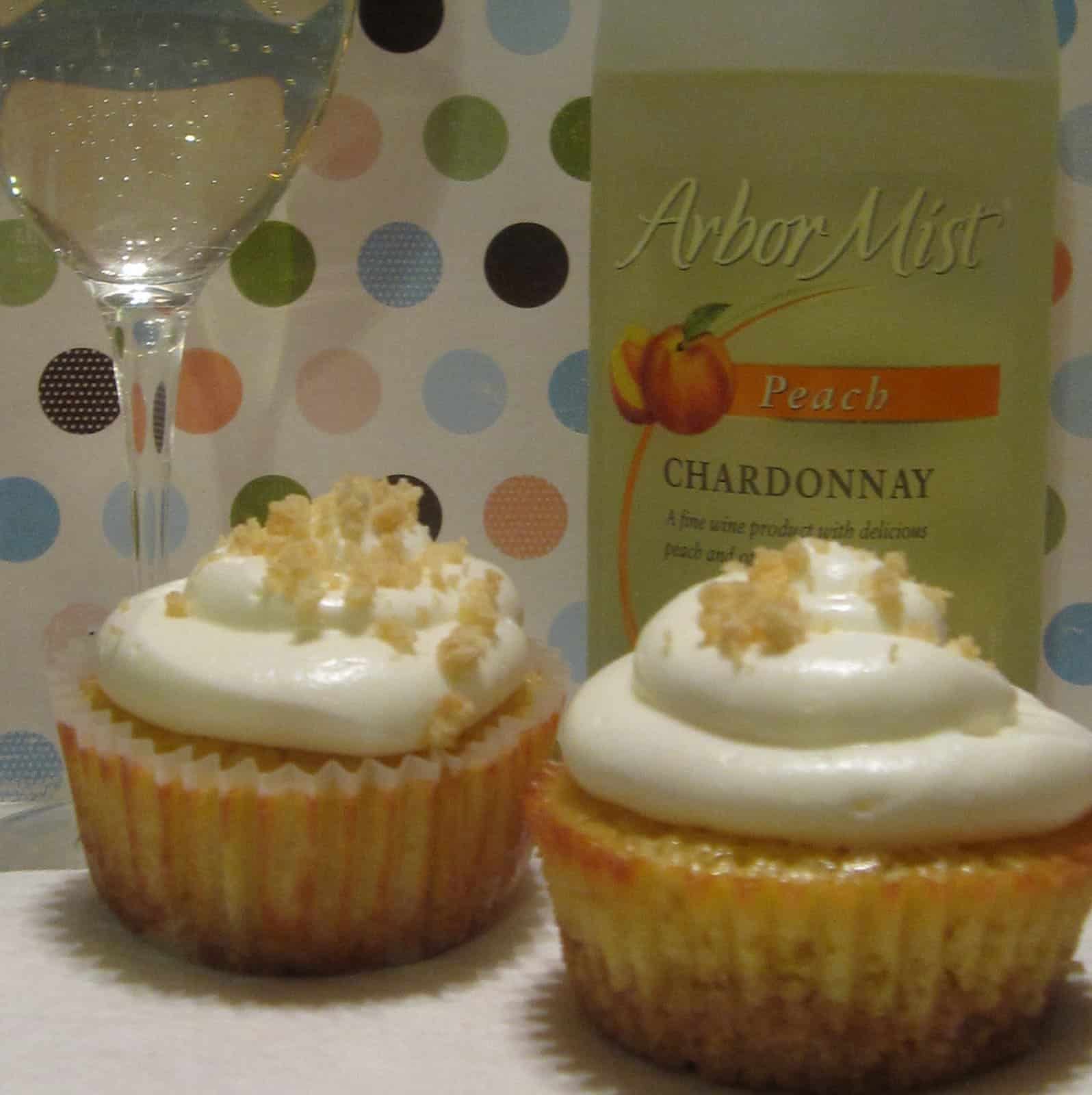 Side view of two Peach Wine Cupcakes in front of a bottle and a glass of chardonnay