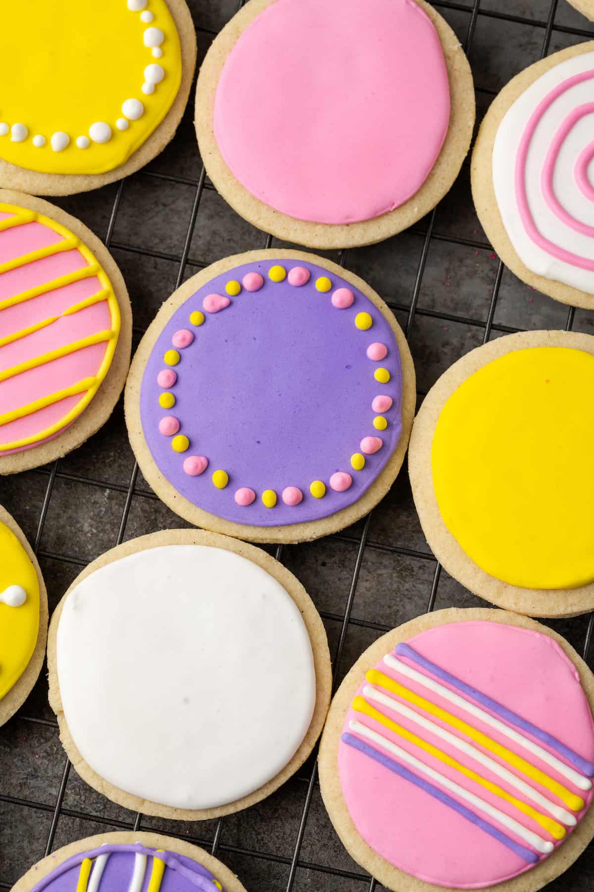 Overhead view of assorted round sugar cookies decorated with royal icing in different colors.