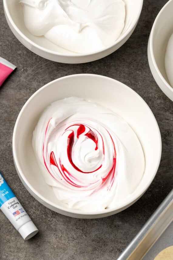 Red food coloring added to royal icing in a white bowl.