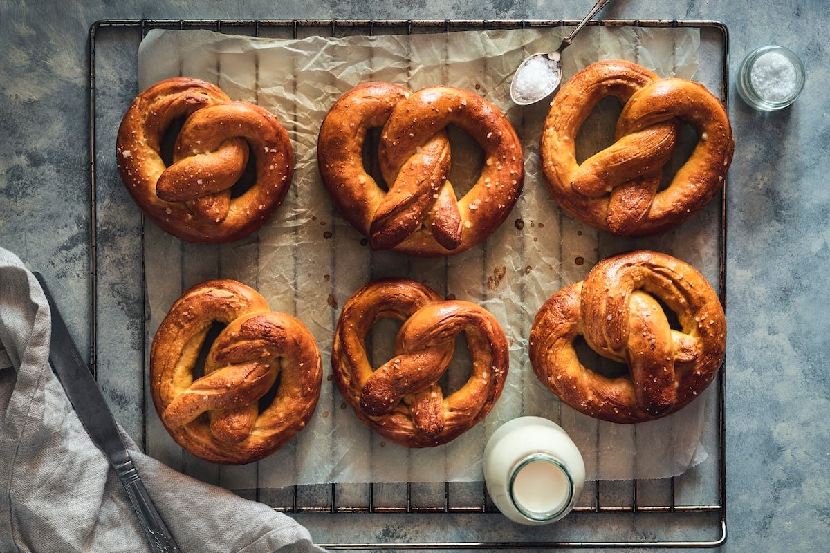 6 homemade soft pretzels on a cooling rack.