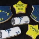 Overhead view of Blue, Yellow and White decorated graduation cookies