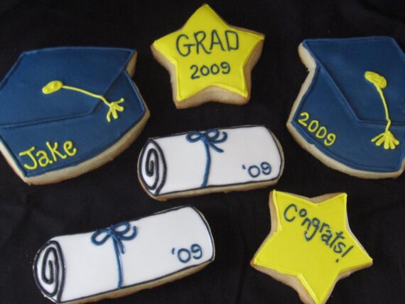Overhead view of Blue, Yellow and White decorated graduation cookies.