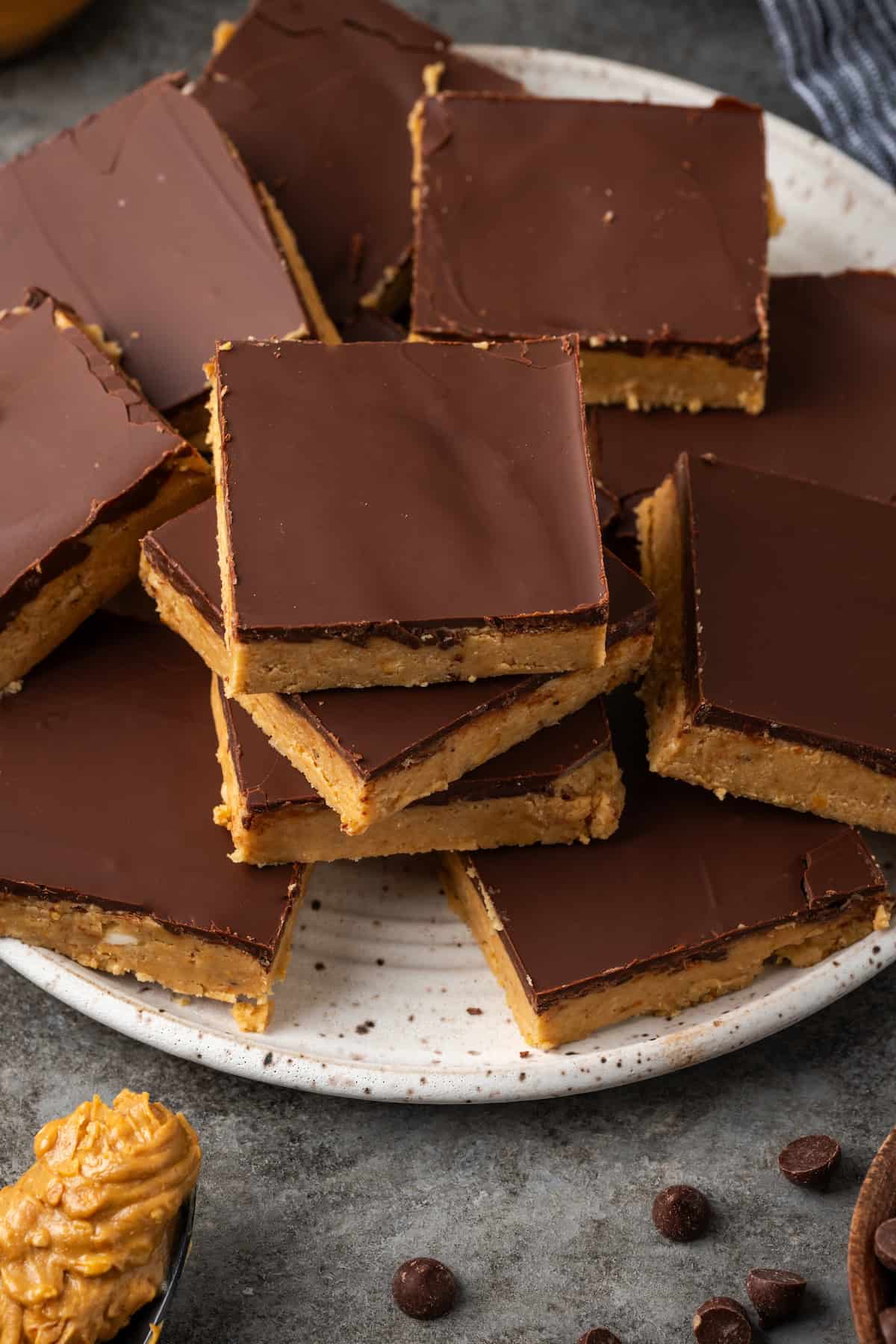 Overhead view of chocolate peanut butter bars stacked on a white plate.