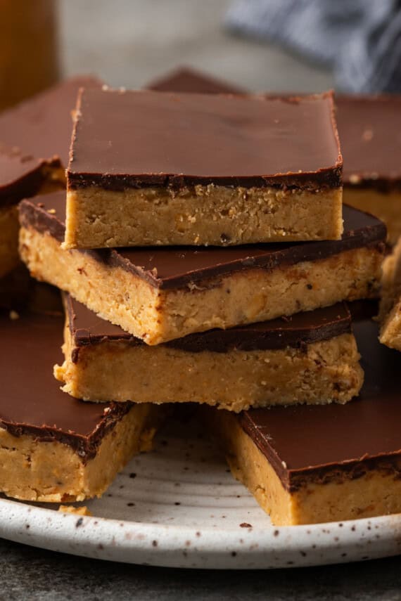 Chocolate peanut butter bars stacked on a white plate.