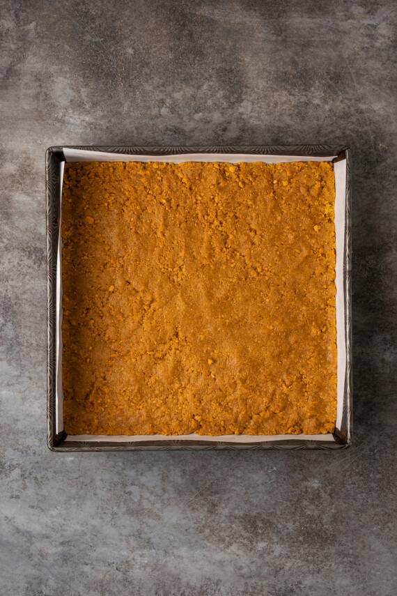 Graham cracker crust pressed into the bottom of a lined square baking pan.