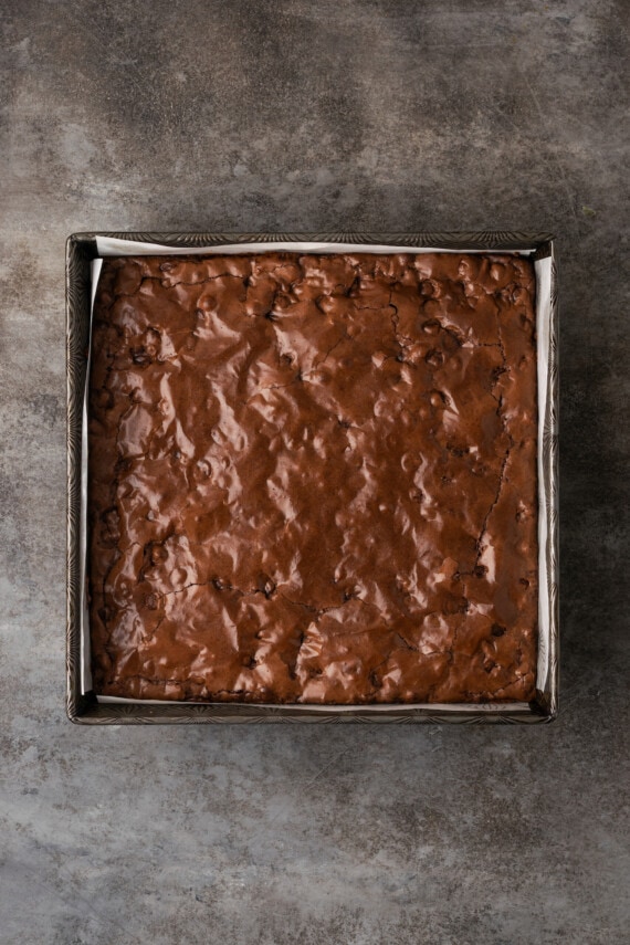 Baked brownies in a lined square baking pan.