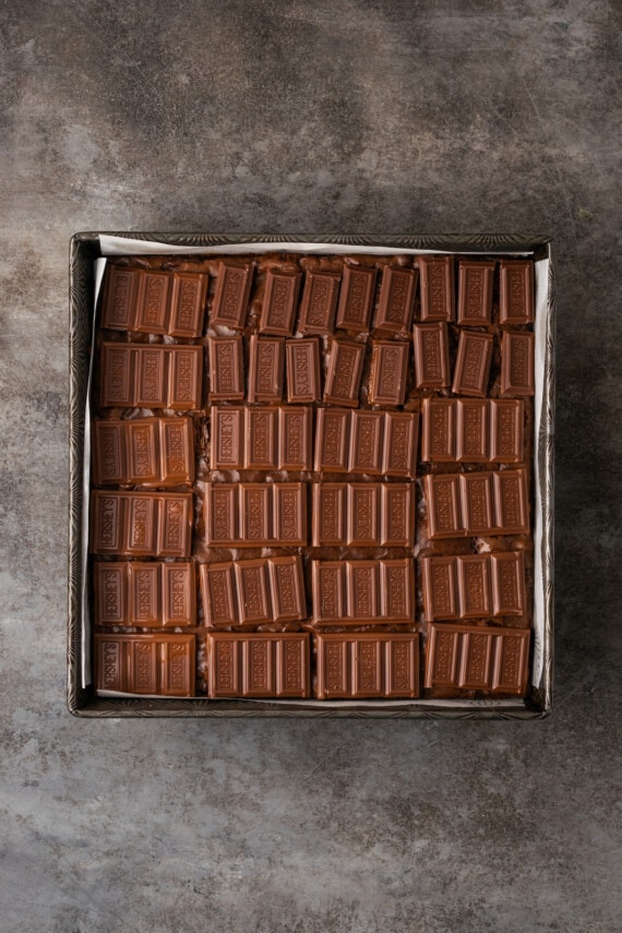 Hershey's chocolate bars layered over baked brownies in a square pan.