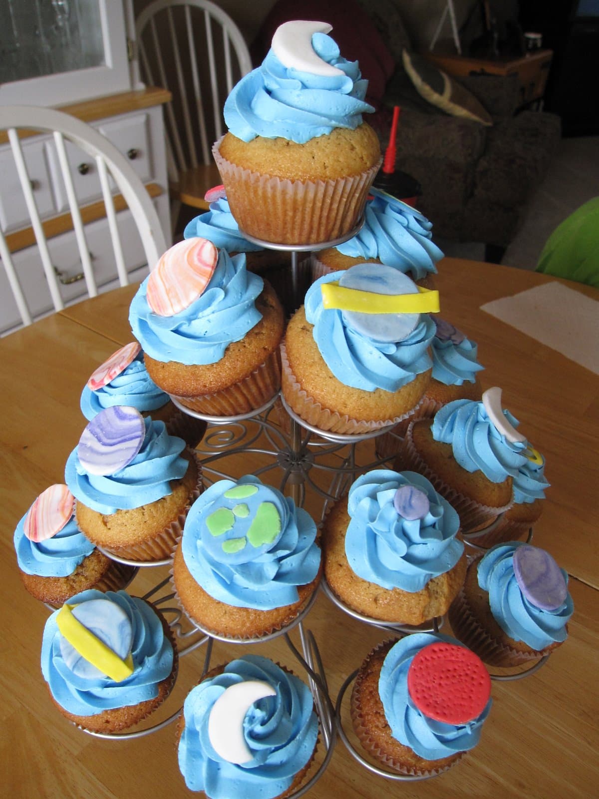 A variety of blue frosted space-themed cupcakes in a cupcake tower