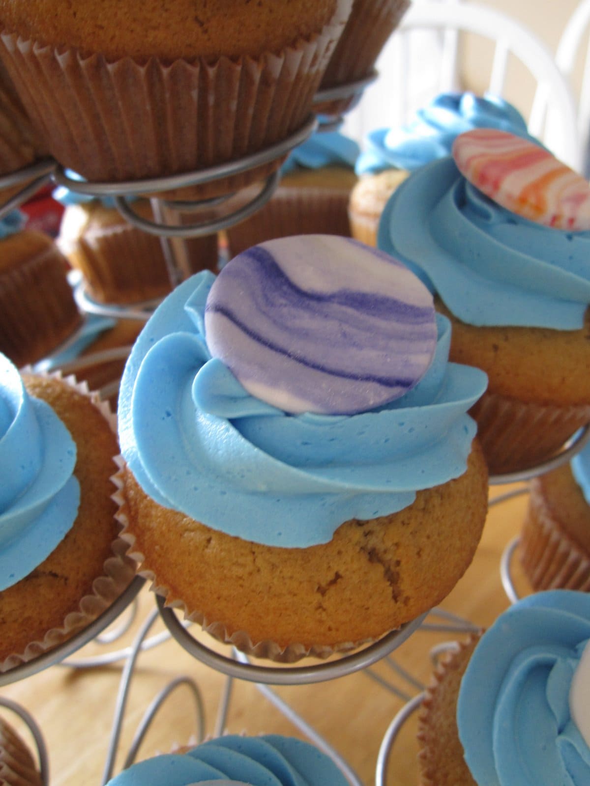 Close-up of a blue frosted cupcake with a purple disc on top
