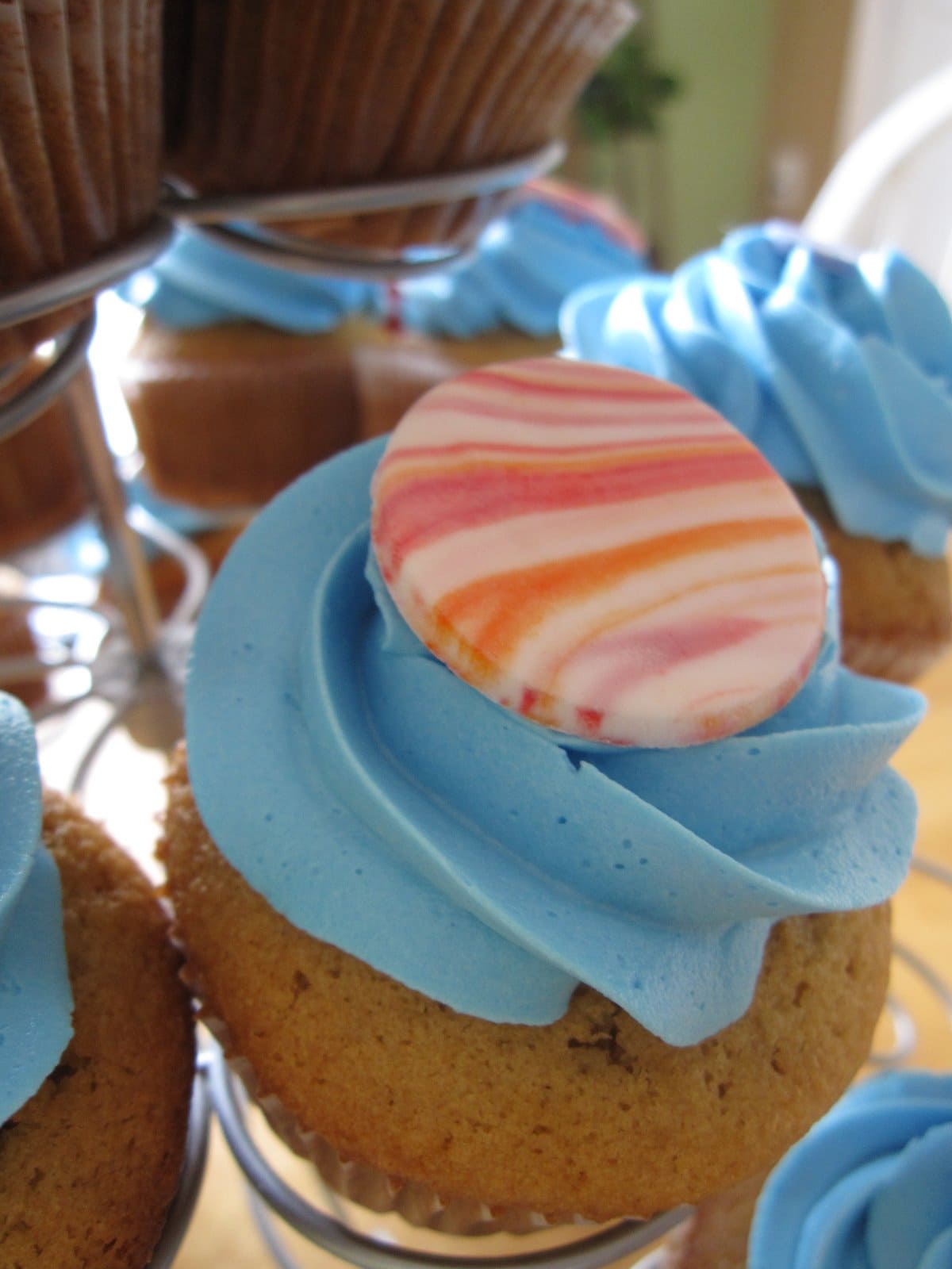 Close-up of a blue frosted cupcake with a colorful disc on top