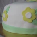 Side view of a cake with white frosting and yellow flowers.
