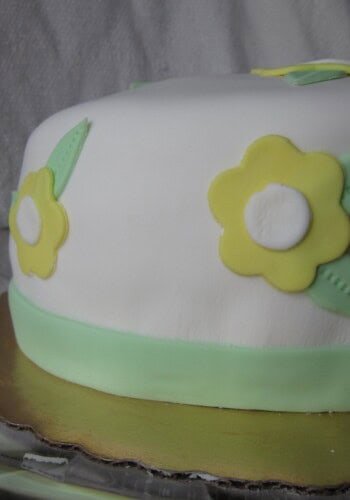 Side view of a cake with white frosting and yellow flowers