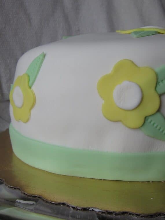 Side view of a cake with white frosting and yellow flowers.