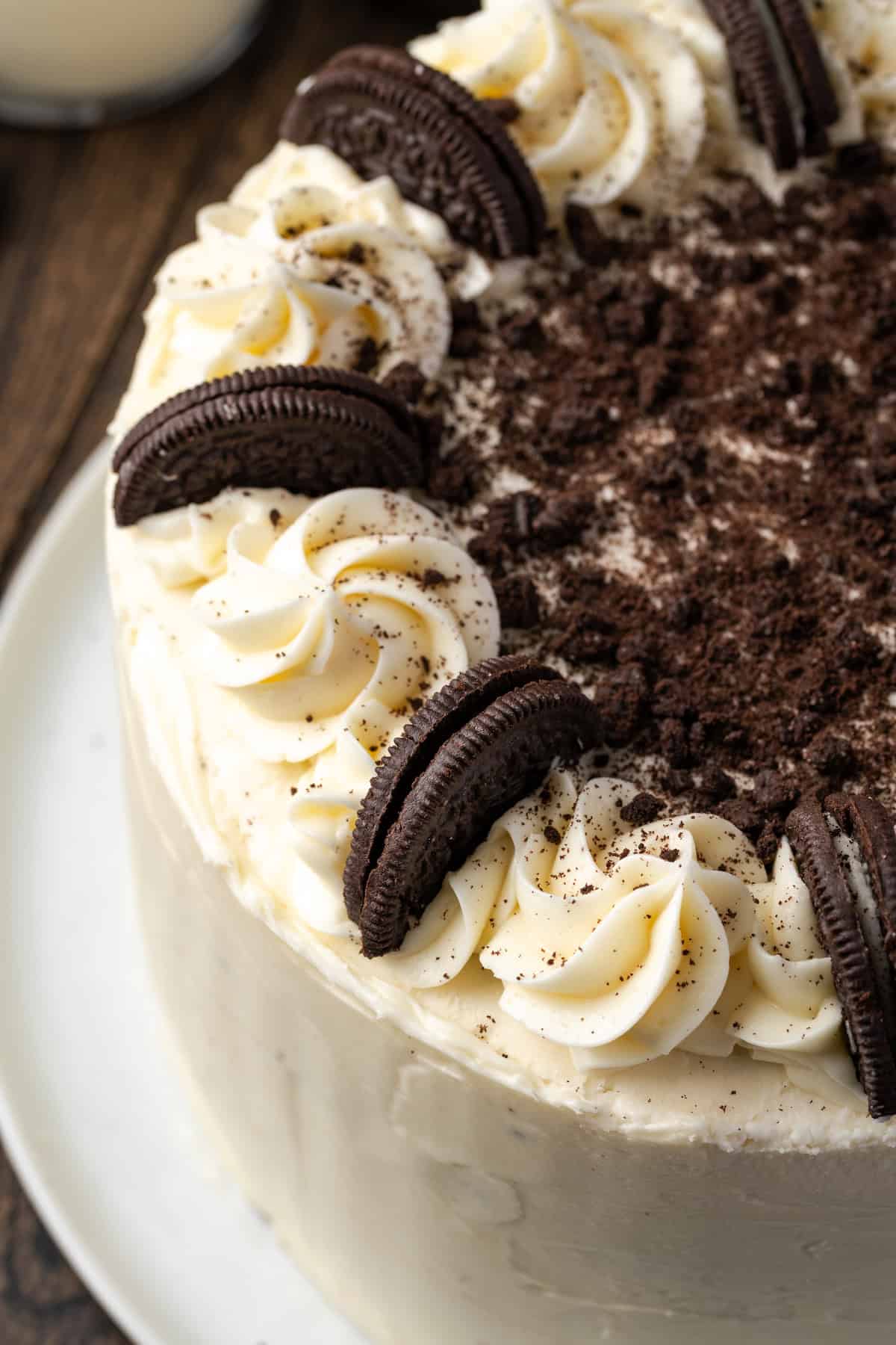 Close up of a frosted cookies and cream cake decorated with vanilla buttercream swirls interspersed with Oreo cookies.