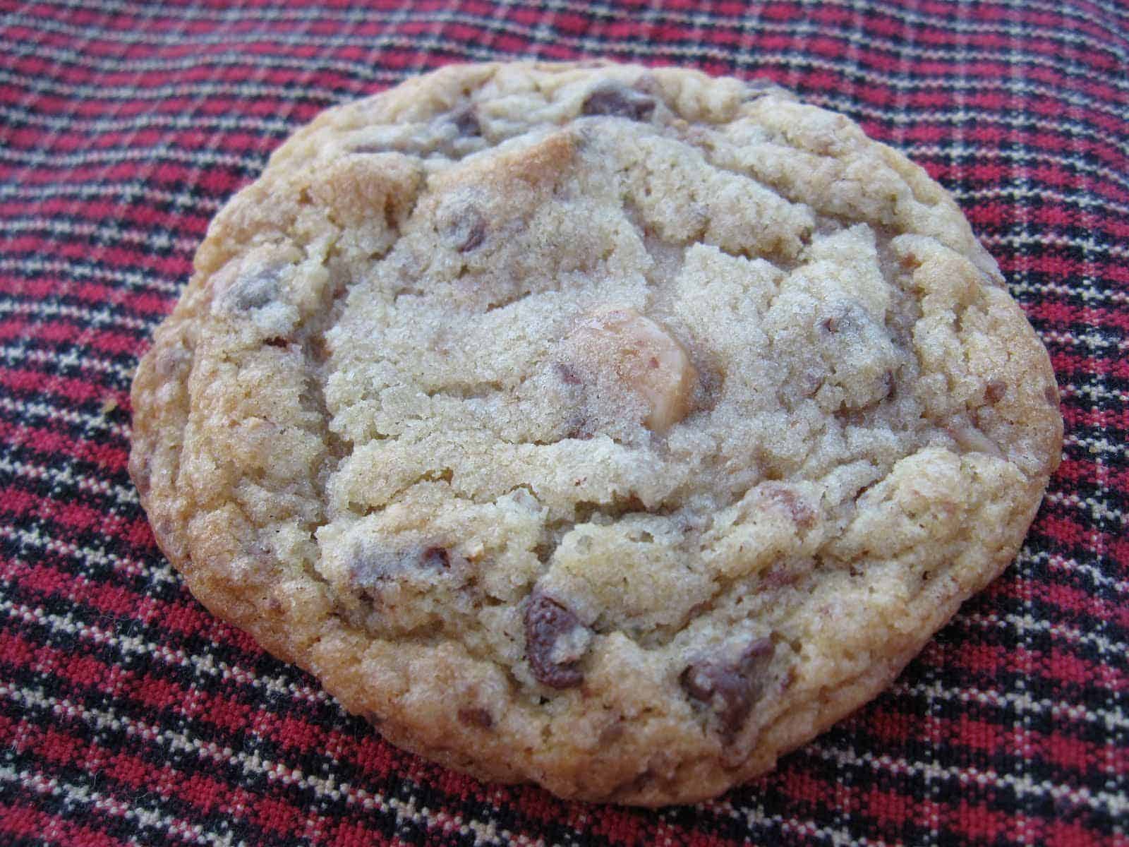 Overhead view of a toffee chip chocolate chip cookie on a plaid background