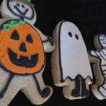 Overhead view of Halloween cookies decorated as a pumpkin boy, ghost, and mummy