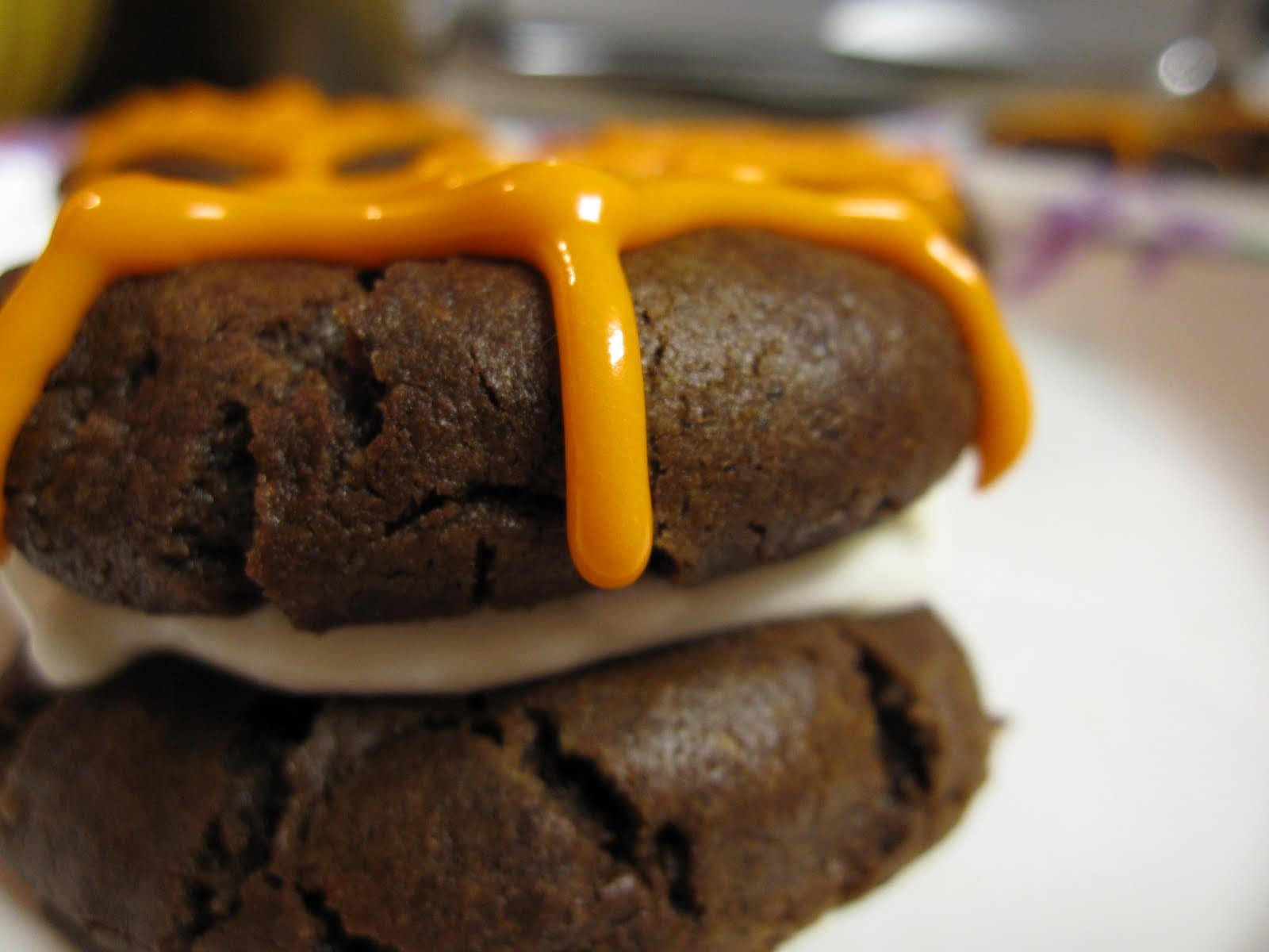 Close-up of a whoopie pie with orange spiderweb frosting