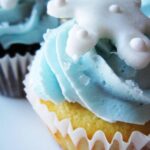 Close-up of a cupcake with blue frosting and a snowflake decoration on top