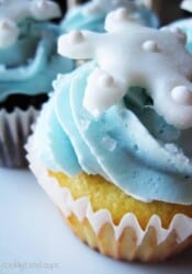 Close-up of a cupcake with blue frosting and a snowflake decoration on top