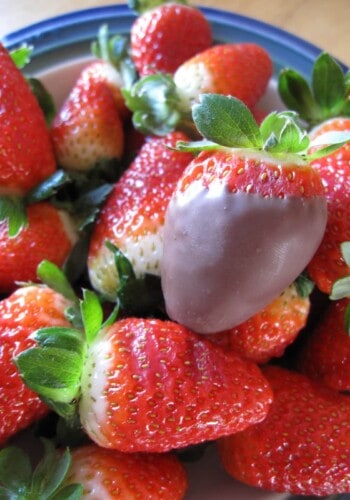 Close-up of a chocolate-dipped strawberry on top of a pile of fresh strawberries