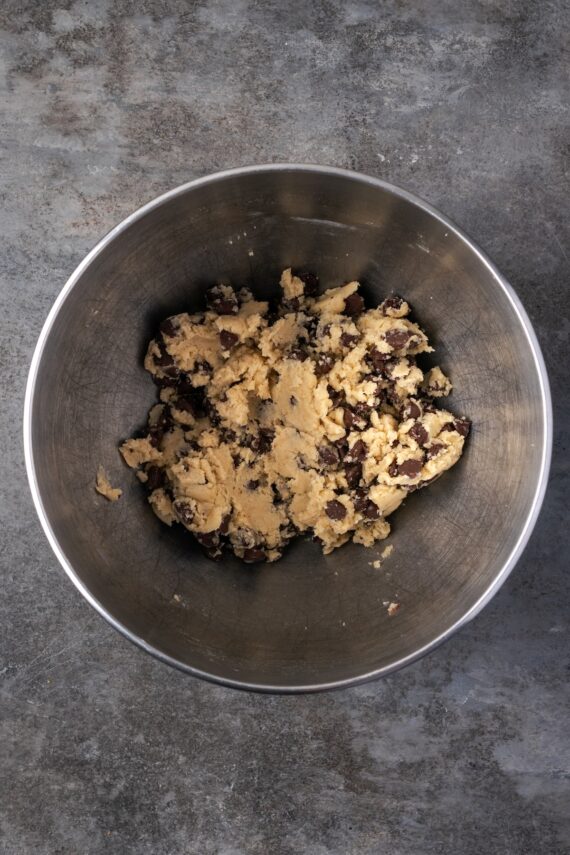 Chocolate chip cookie dough in a metal bowl.