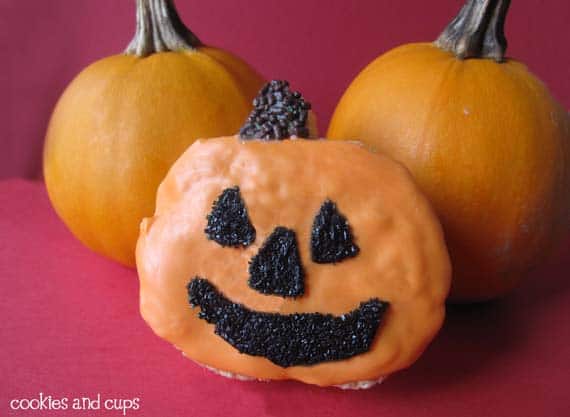 A krispie treat decorated like a pumpkin in front of two real pumpkins