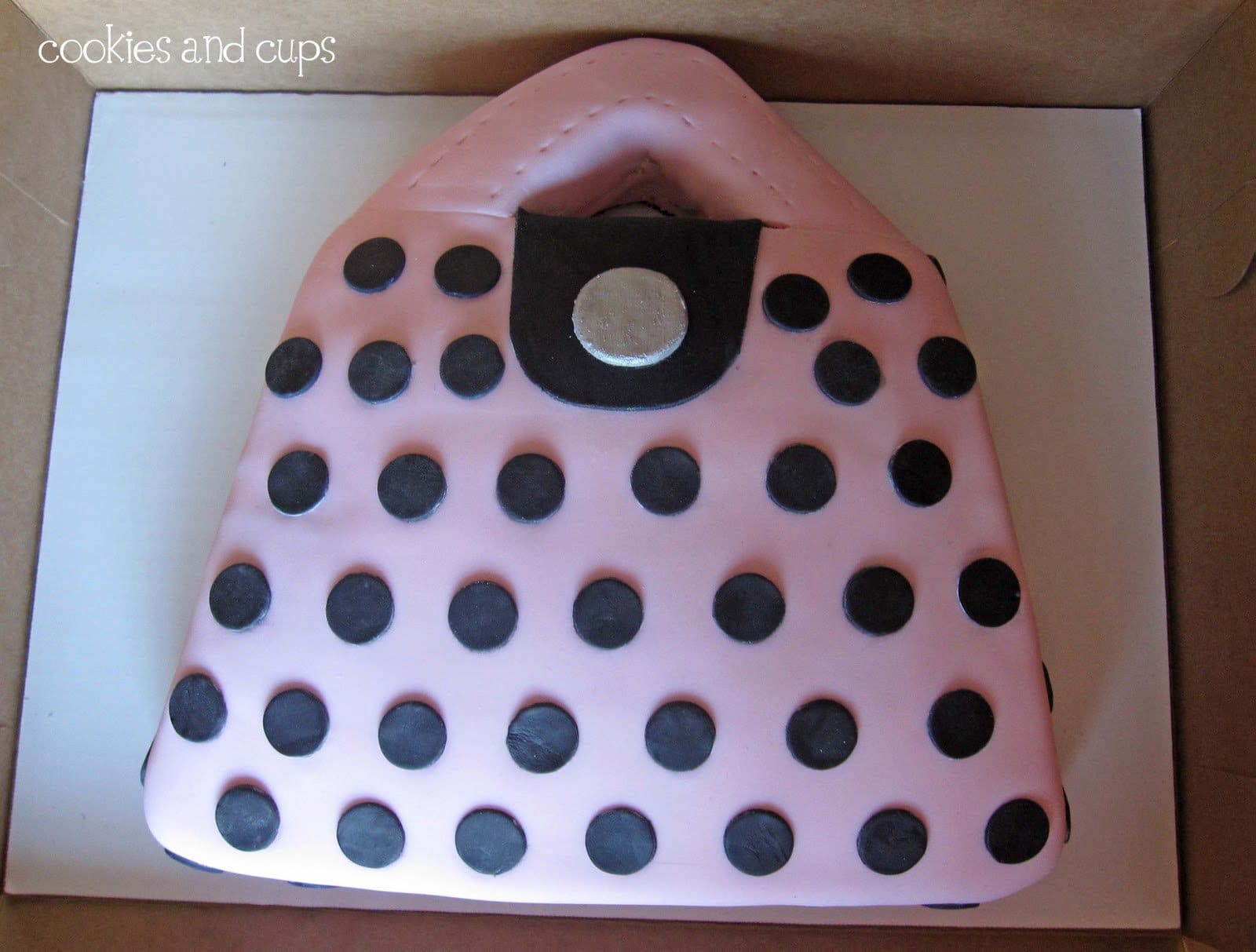 Top view of a cake decorated as a pink purse with black polka dots