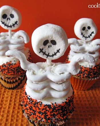 Overhead view of 3 cupcakes with skeleton toppers