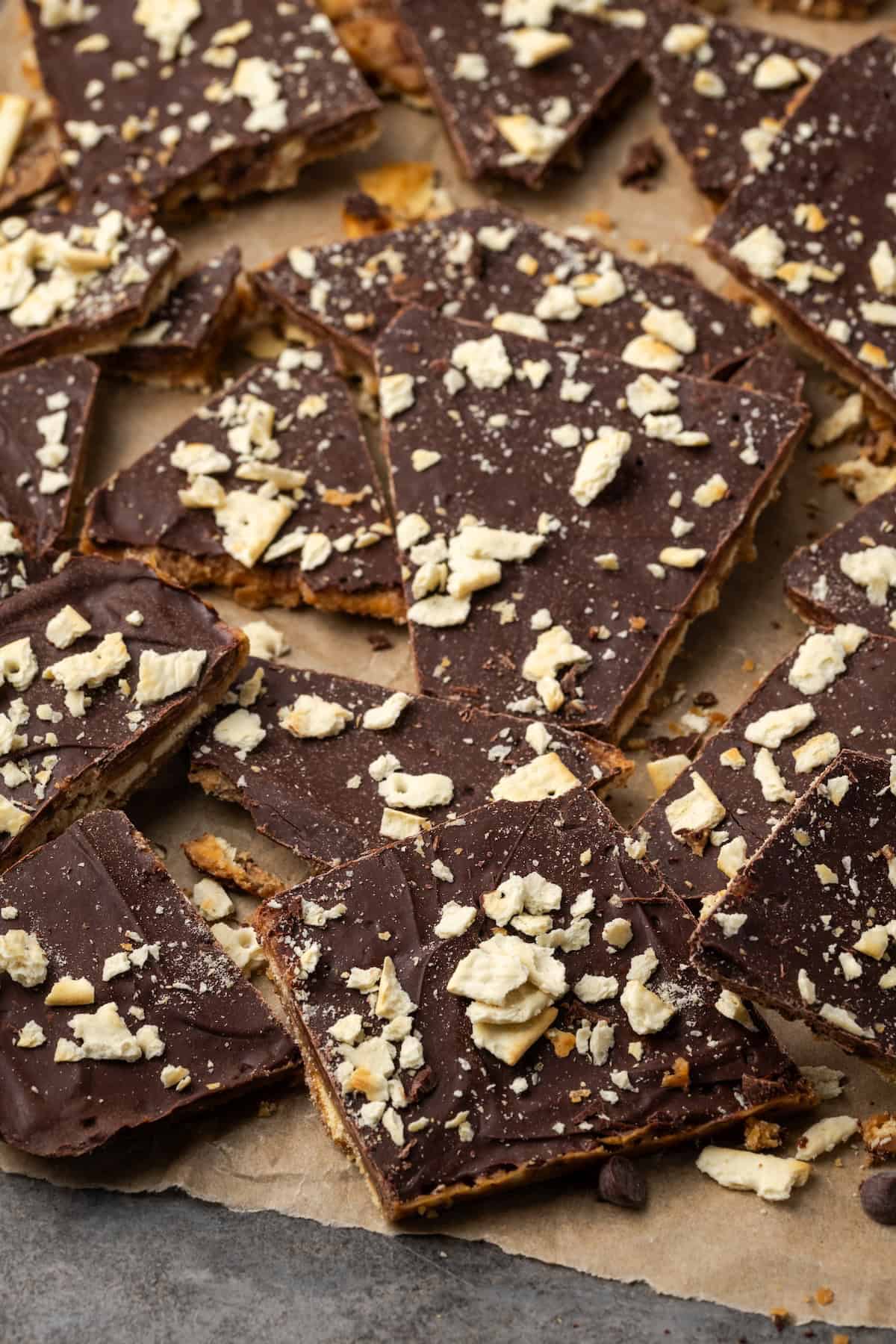Assorted saltine toffee pieces scattered on a sheet of parchment paper.