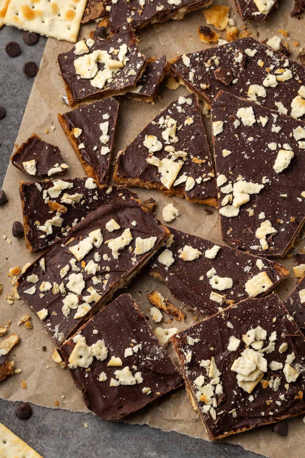 Assorted saltine toffee pieces scattered on a sheet of parchment paper.
