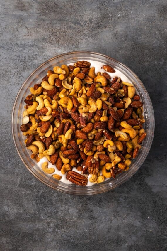 Mixed nuts added to the cinnamon meringue mixture in a bowl.