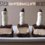 Side view of three toasted marshmallow brownies with marshmallow snowmen on top