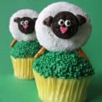 Two Sheep Cupcake Toppers on Top of Two Cupcakes with Green Frosting and Green Sprinkles