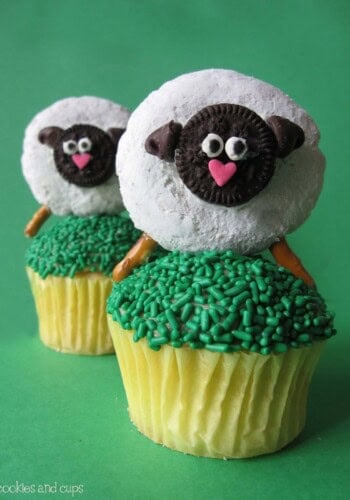 Two Sheep Cupcake Toppers on Top of Two Cupcakes with Green Frosting and Green Sprinkles