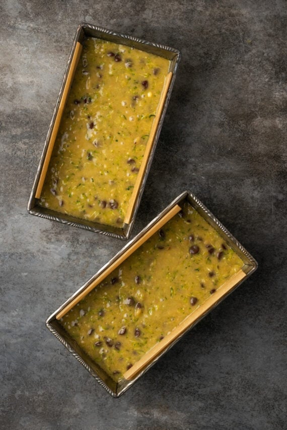 Overhead view of two loaf pans filled with chocolate chip zucchini bread batter.