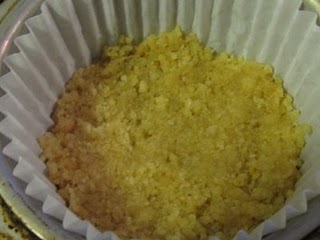 Crushed shortbread cookie crumbs pressed into a crust in the bottom of a cupcake liner.