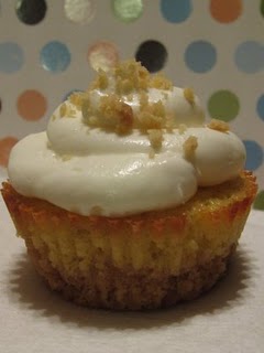 A peach wine cupcake topped with cream cheese frosting and garnished with shortbread crumbs.