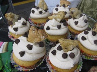 An assortment of cookie dough cupcakes topped with cookie dough frosting, chocolate chips, and cookie wedges.