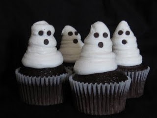 Halloween ghost cupcakes topped with white buttercream decorated to look like faces.