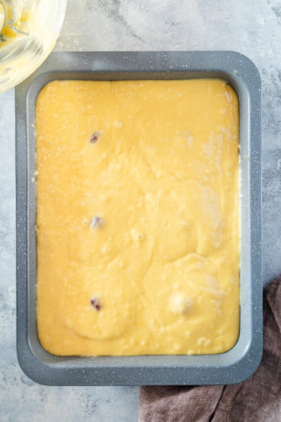 Cake batter on top of a tray of pineapple slices.