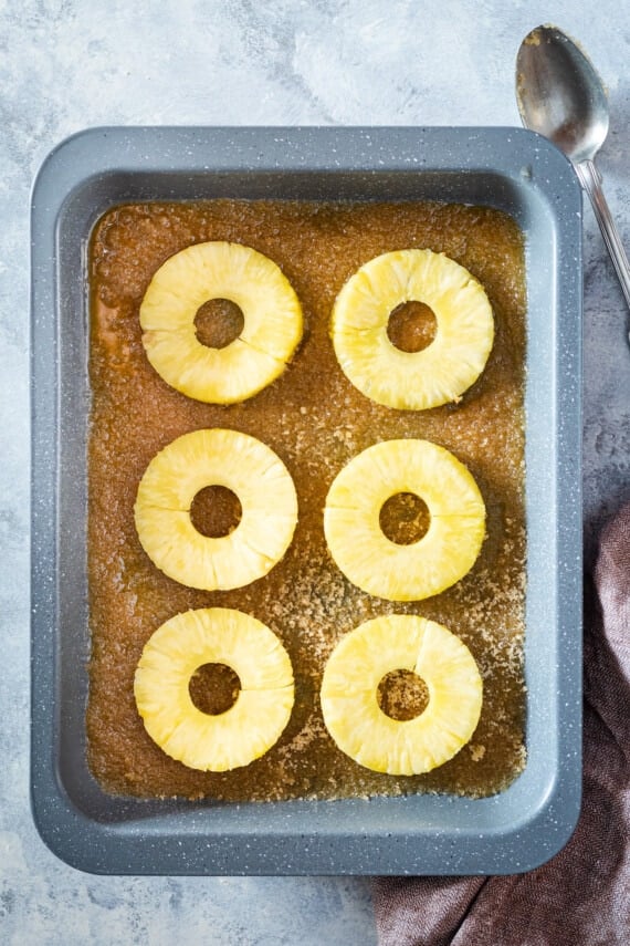 Pineapple slices on brown sugar in a pan.