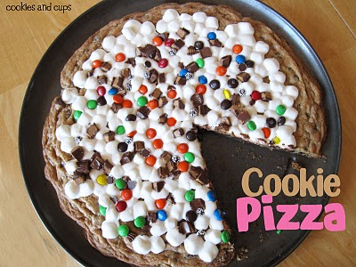 Overhead view of a cookie pizza in a pan with a slice removed