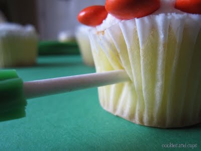 Candy stick being poked into the side of a cupcake paper