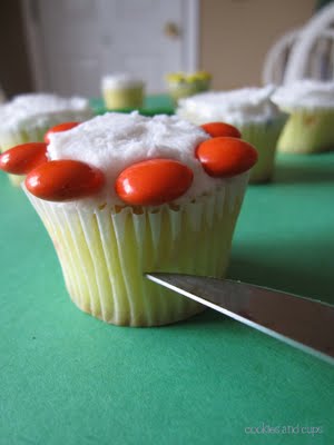 Side view of vanilla frosted cupcake with orange M&M's