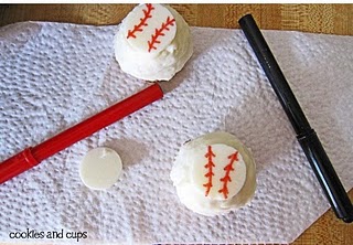 Two vanilla cupcakes with baseball decorations on a paper towel with two foodwriters