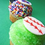 A baseball, flower and soccer ball cupcake arranged in a line