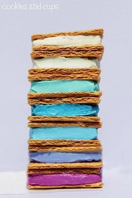 A stack of graham crackers with a rainbow of frosting colors in between, stacked